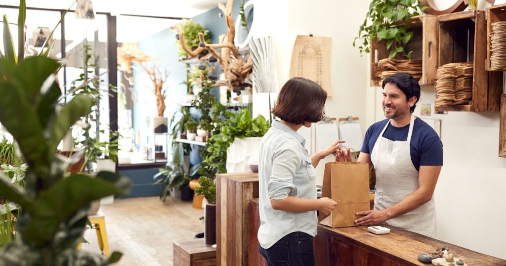 A merchant selling trending products to a customer inside his shop.